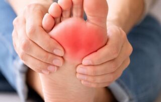 Person holding the ball of their foot showing forefoot pain and inflammation