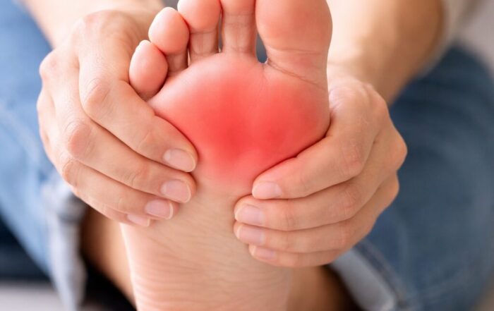Person holding the ball of their foot showing forefoot pain and inflammation