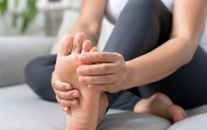 Close-up of a person holding their bare foot and toes, illustrating discomfort, numbness, or tingling in the toes.